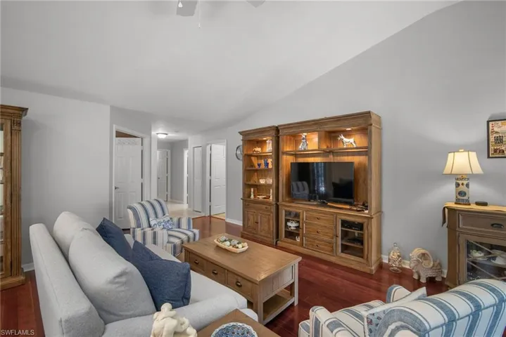 Living room featuring ceiling fan, vaulted ceiling, and dark hardwood / wood-style flooring
