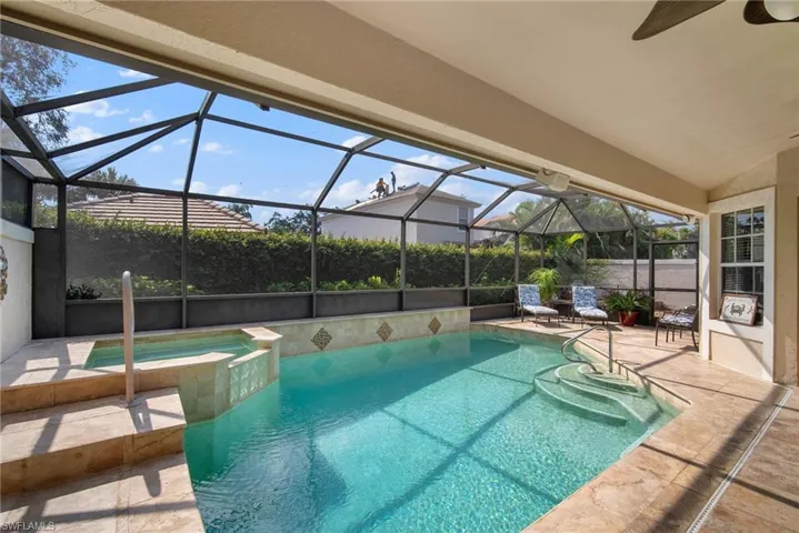 View of pool featuring a patio area, ceiling fan, an in ground hot tub, and glass enclosure