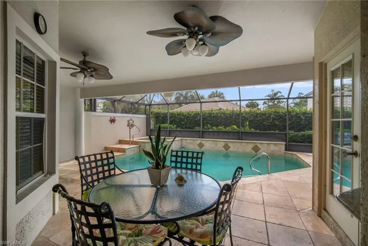 View of pool featuring a patio area, glass enclosure, and ceiling fan