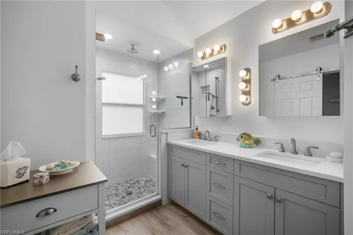 Bathroom featuring a shower with door, hardwood / wood-style flooring, vanity, and vaulted ceiling