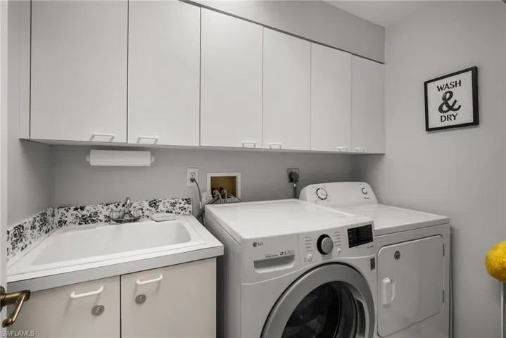 Laundry room featuring cabinets, washer and dryer, and sink