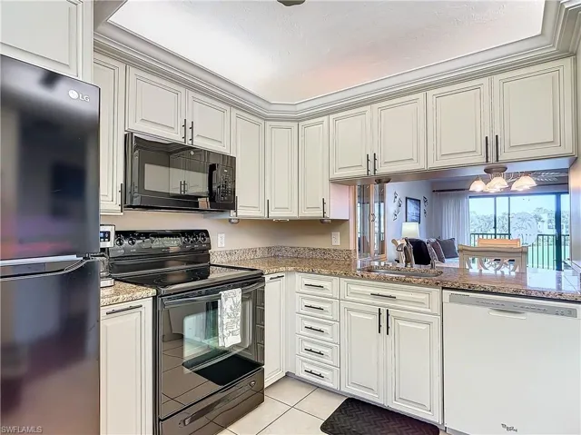Kitchen featuring black appliances, sink, light tile patterned floors, kitchen peninsula, and light stone countertops
