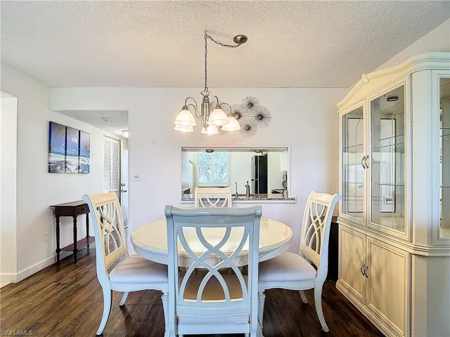 Dining space with dark hardwood / wood-style flooring, a chandelier, and a textured ceiling