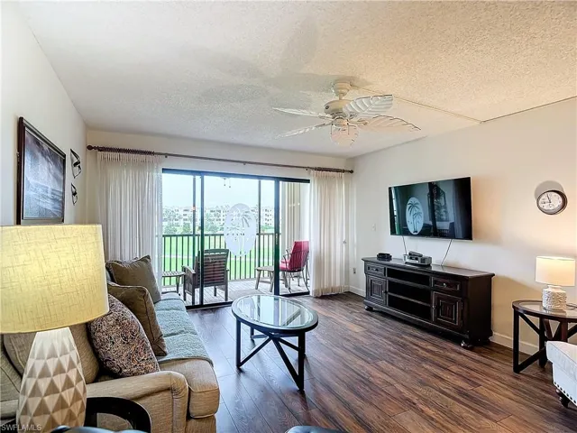 Living room featuring ceiling fan, dark hardwood / wood-style floors, and a textured ceiling