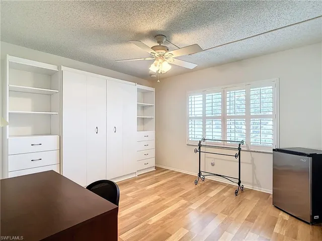 Unfurnished office featuring ceiling fan, a textured ceiling, and light wood-type flooring
