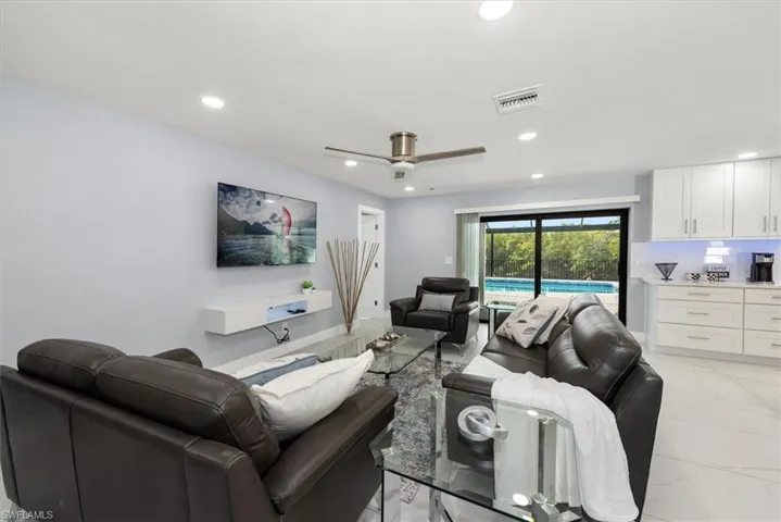 Living room featuring recessed lighting, light marble finish floors, and a ceiling fan