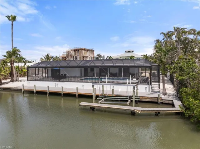 Rear view of property featuring a community pool, a water view, and a lanai
