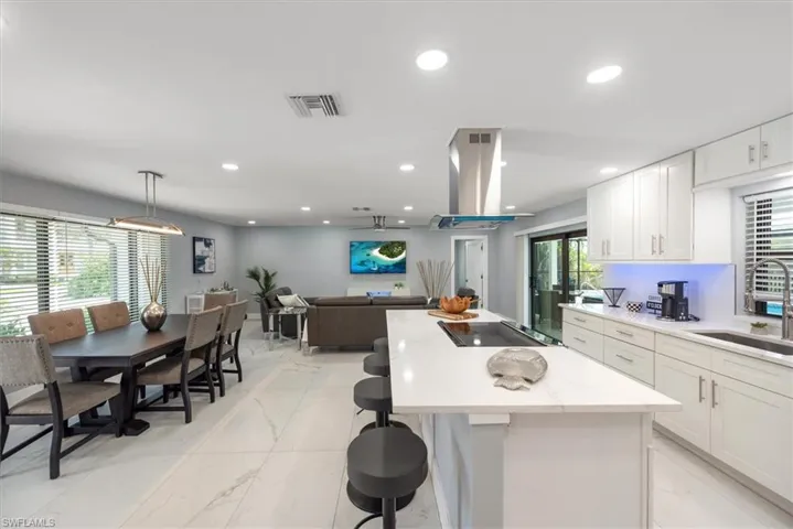 Kitchen with light marble finish floors, island range hood, a sink, a kitchen island, and recessed lighting