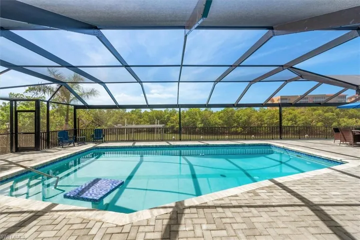 View of swimming pool with a patio area and glass enclosure