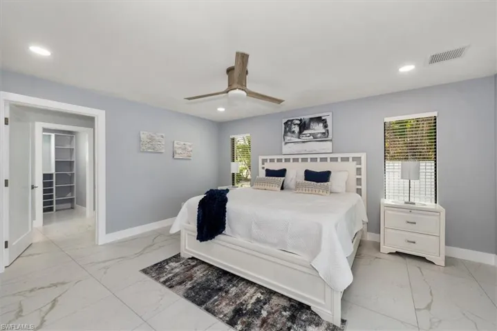 Bedroom with light marble finish floors, baseboards, recessed lighting, and ceiling fan
