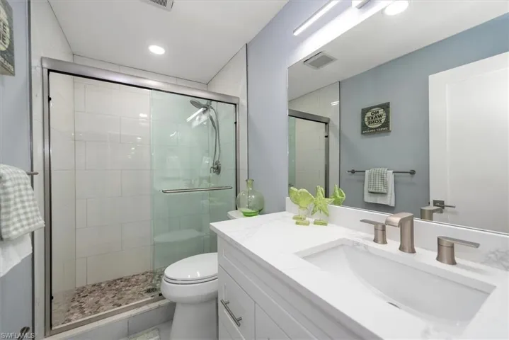 Full bath with a stall shower, toilet, vanity, and recessed lighting