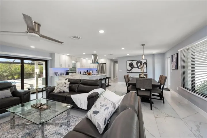 Living area featuring light marble finish floors, recessed lighting, baseboards, and a ceiling fan
