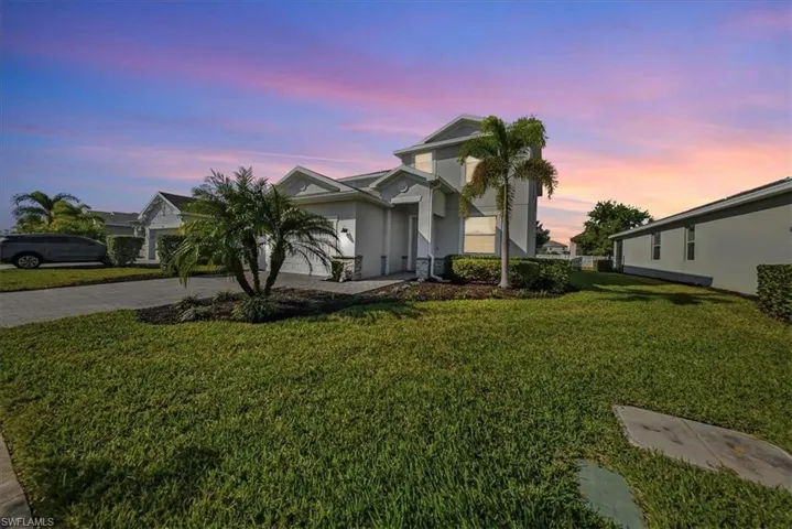 View of front of house featuring decorative driveway, stucco siding, a front lawn, and an attached garage