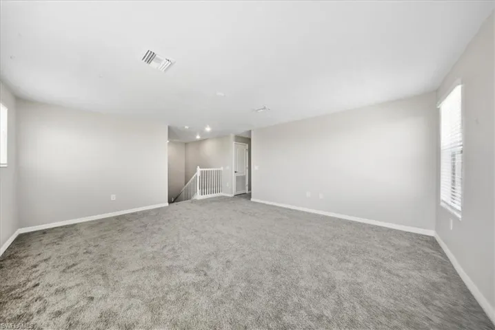 Spare room featuring light colored carpet and a textured ceiling