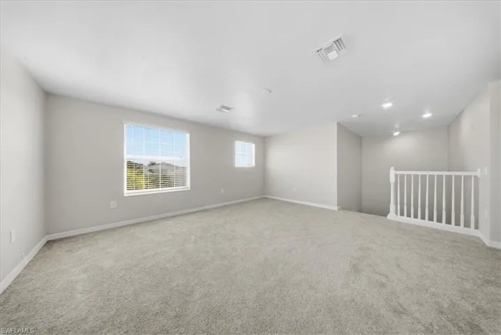 Carpeted spare room featuring baseboards