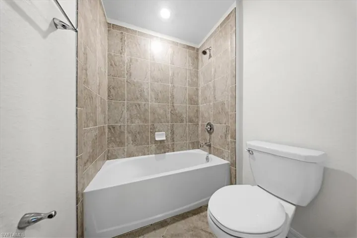 Full bath with double vanity, shower / bath combination, and light tile patterned floors