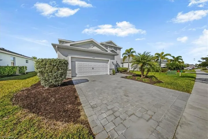 View of front of house with a front lawn, decorative driveway, stucco siding, an attached garage, and stone siding