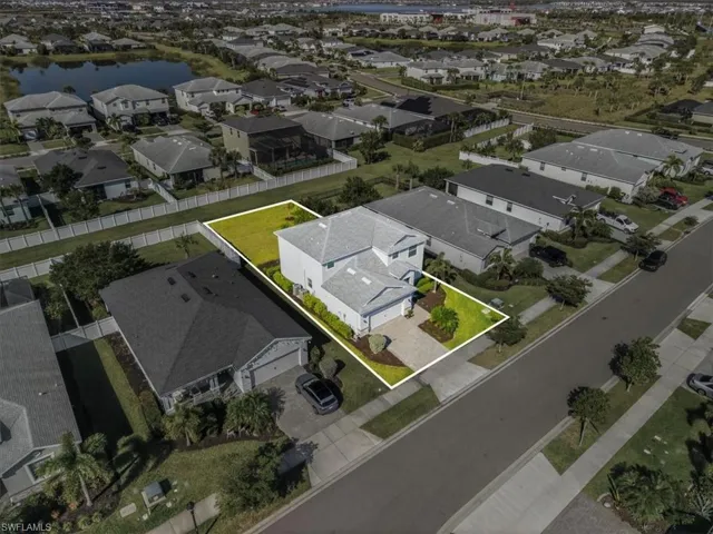 Aerial perspective of suburban area with property parcel outlined and a nearby body of water