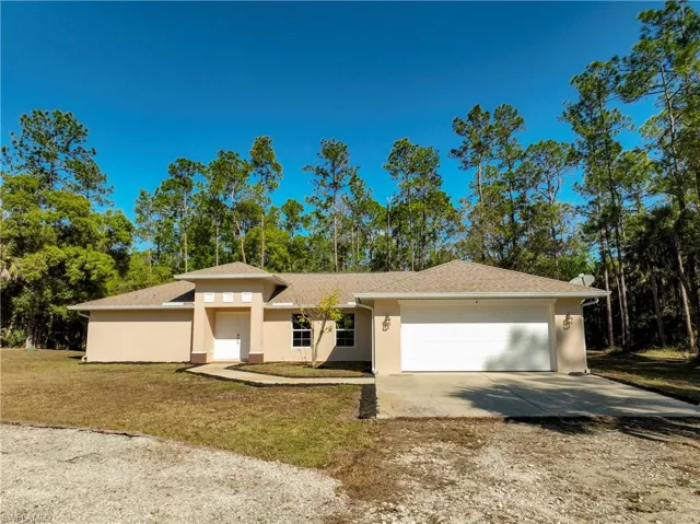 View of front of house featuring a front yard, circular driveway, and attached 2 car garage.
