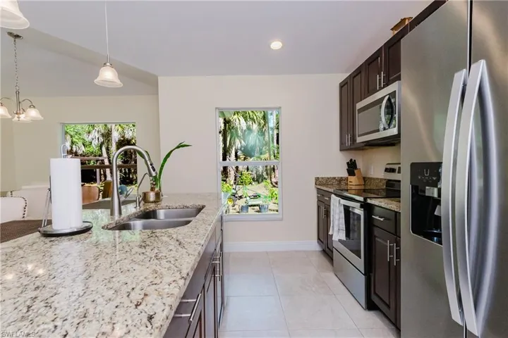 Spacious open Kitchen, ADA compliant, with wood cabinets, stainless steel appliances, decorative light fixtures, and light granite counters.