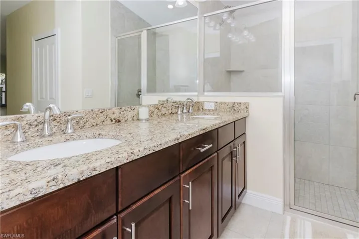 Master Bathroom featuring a walk-in shower, double vanity, and granite counter top.