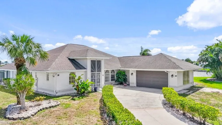 View of front facade featuring an attached garage, a shingled roof, concrete driveway, and a front yard