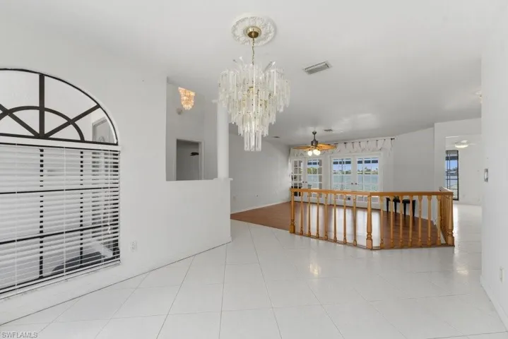 Empty room with ceiling fan, hanging lights, and light tile patterned floors
