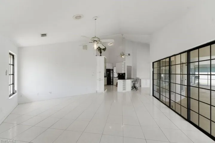 Unfurnished living room with vaulted ceiling, a ceiling fan, and light tile patterned flooring