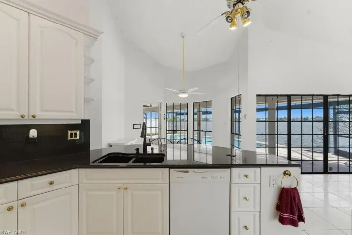 Kitchen with dishwasher, a peninsula, open shelves, ceiling fan, and white cabinetry