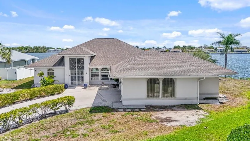 Back of house featuring stucco siding, roof with shingles, and a water view