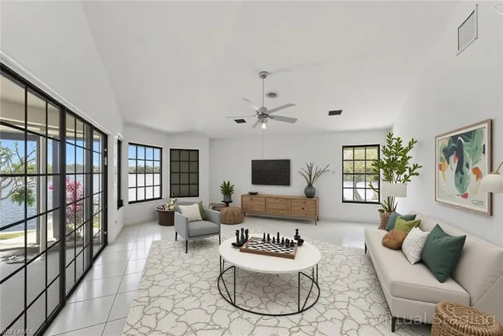 Living room featuring vaulted ceiling, a ceiling fan, and light tile patterned floors