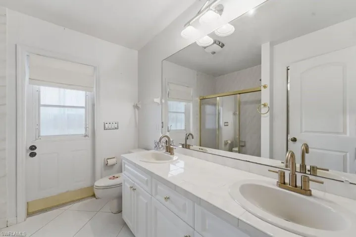 Bathroom featuring double vanity, a shower with shower door, and light tile patterned flooring