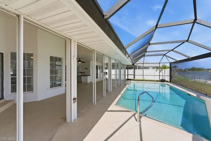 View of pool with glass enclosure, a sunroom, and patio surround