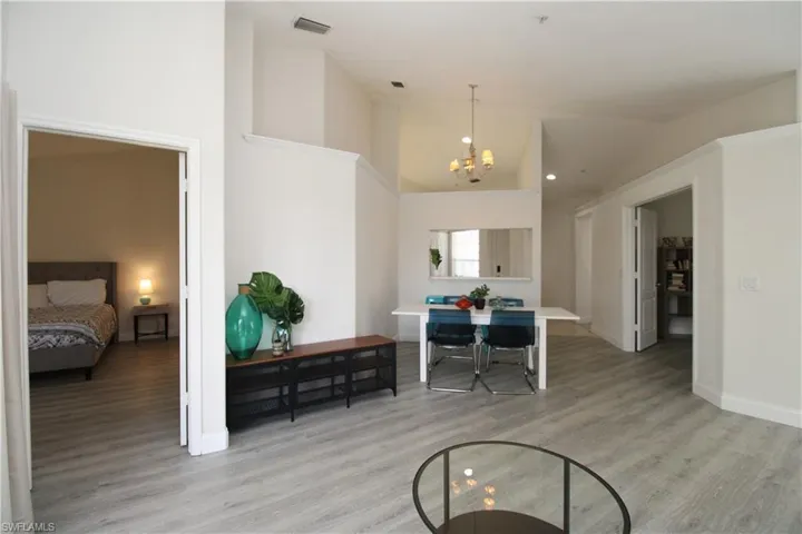 Office space featuring high vaulted ceiling, light wood-type flooring, and an inviting chandelier