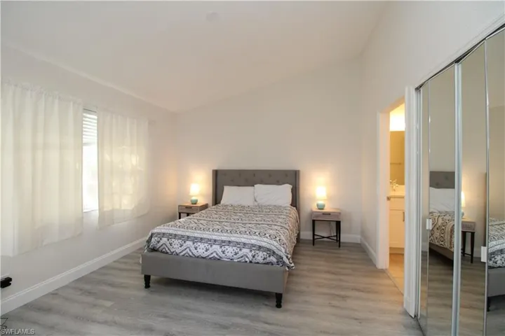Bedroom with a closet, light hardwood / wood-style flooring, and lofted ceiling
