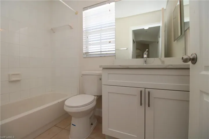 Full bathroom with vanity, washtub / shower combination, tile patterned floors, and toilet