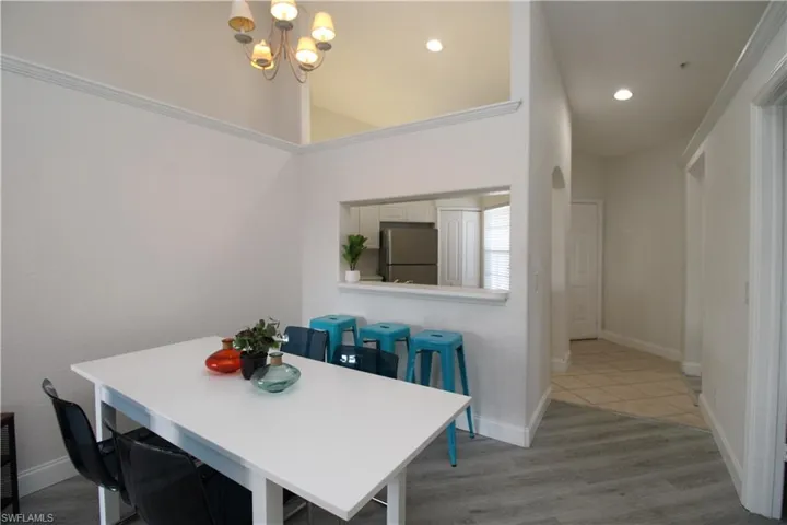 Dining room featuring a high ceiling, a notable chandelier, light hardwood / wood-style floors, and crown molding