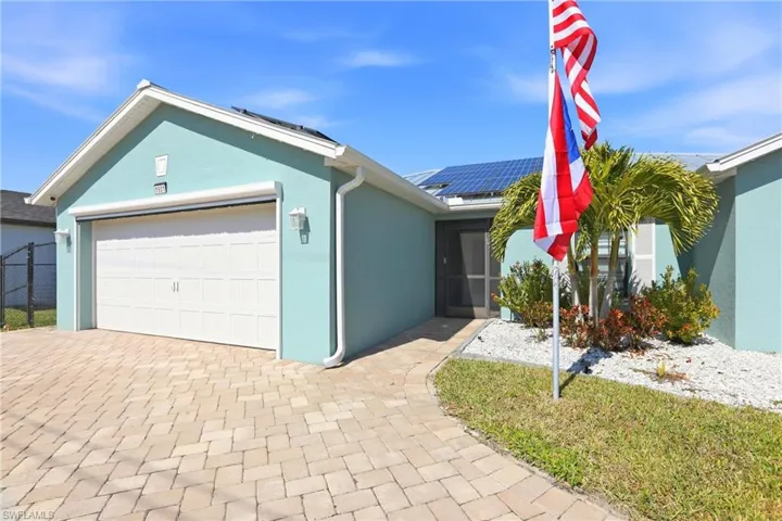 Single story home with solar panels, stucco siding, decorative driveway, an attached garage, and a sunroom
