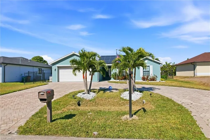 Ranch-style home featuring solar panels, curved driveway, stucco siding, and an attached garage