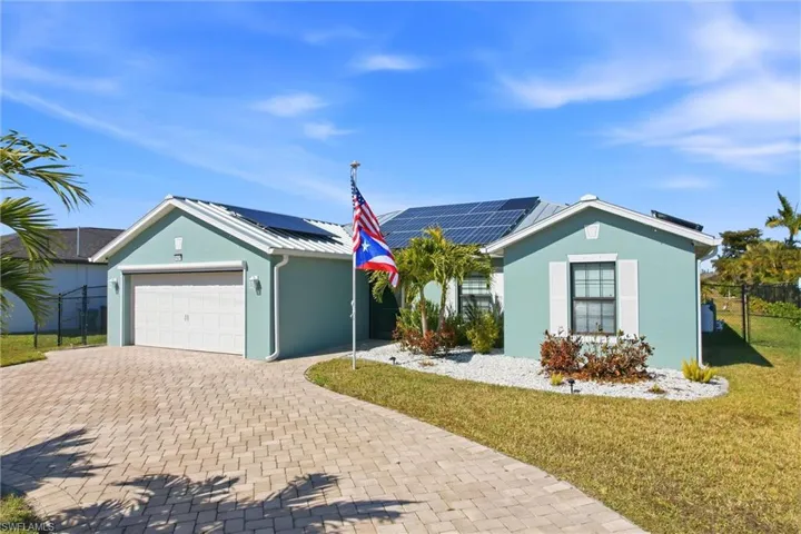 Ranch-style house with roof mounted solar panels, decorative driveway, stucco siding, and an attached garage