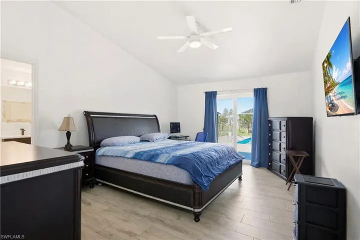 Bedroom featuring vaulted ceiling, light wood-type flooring, access to exterior, and ceiling fan