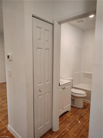 Bathroom featuring wood-look tile flooring, a white vanity with integrated sink, and a white toilet