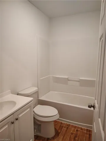 Bathroom featuring a white vanity with integrated sink, white toilet, and a white tub/shower combination with wall surround