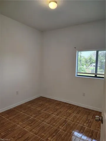Room with wood-look tile flooring, white baseboards, and neutral wall paint