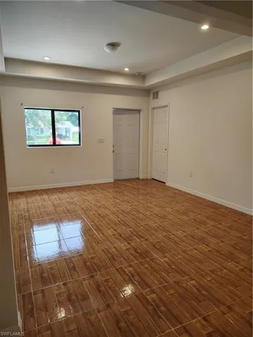 Spacious room featuring wood-finish tile flooring, recessed lighting, and a tray ceiling
