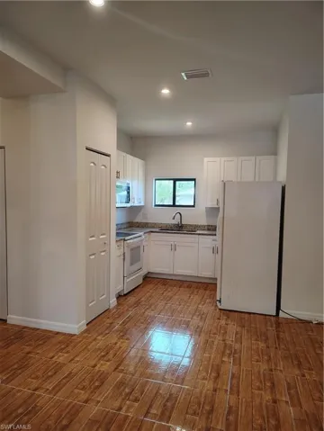 Kitchen featuring white cabinetry, granite countertops, and wood-finish flooring