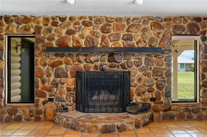 Floor-to-ceiling river rock fireplace with a dark wood mantel and a metal fire screen