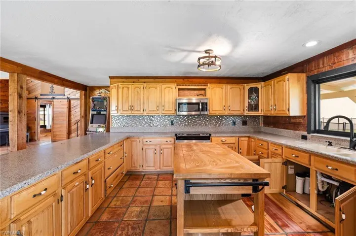 Kitchen featuring natural wood cabinetry, light-toned countertops, and a tiled backsplash