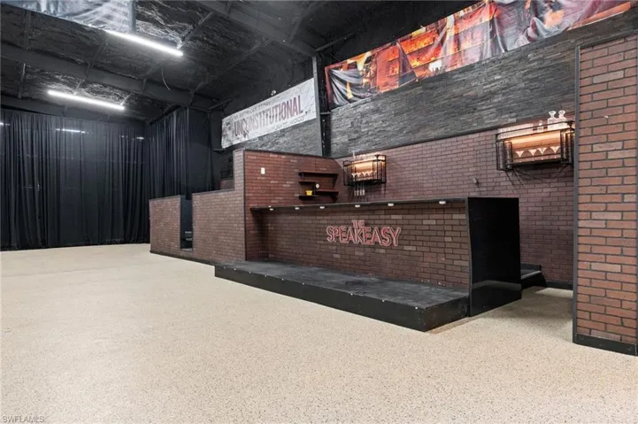 Industrial-style interior featuring a brick-patterned bar structure with a "SPEAKEASY" sign