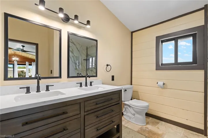 Bathroom featuring a dual vanity with rectangular undermount sinks, stone-finish countertop, and matte black fixtures